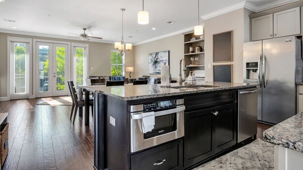 A modern kitchen with a large island, stainless steel appliances, and a dining area with a view of the outdoors. - The Midtown Haven, Pets Welcome! (Tallahassee)