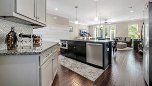 A modern kitchen with a central island, stainless steel appliances, and pendant lighting. - The Midtown Haven, Pets Welcome! (Tallahassee)