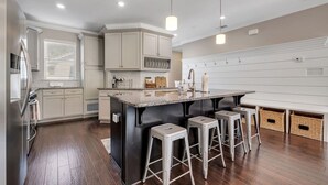 A modern kitchen with a central island, bar stools, and a built-in oven. - The Midtown Haven, Pets Welcome! (Tallahassee)