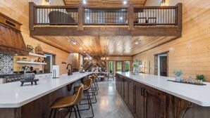 A spacious kitchen with a long island, bar stools, and a view of the outdoors.