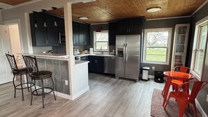 Een moderne keuken met donkere kastjes, een roestvrijstalen koelkast en een eethoek met rode stoelen.