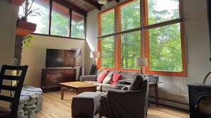 Un salón amplio con un gran ventanal, techo de madera y una chimenea acogedora.