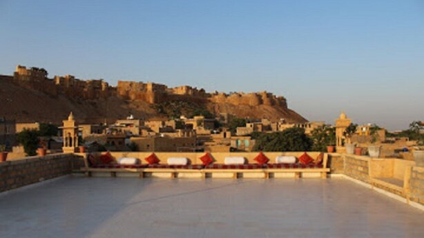 A rooftop terrace with a view of a historic fort and surrounding buildings.