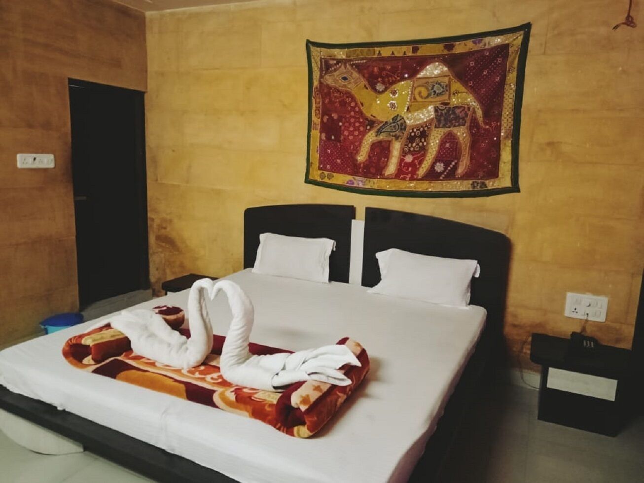 A hotel room with a bed, a wall tapestry, and a nightstand.