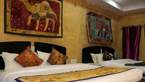 A hotel room with two beds, each with white bedding and decorative pillows. There are two large wall hangings depicting animals.
