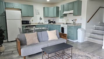 Una cocina moderna con armarios color turquesa, un sofá gris y una mesa de centro de madera.