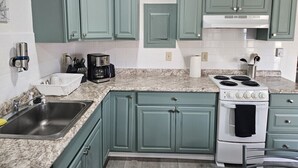 A kitchen with teal cabinets, a white stove, and a granite countertop. - Apartment Close to Hospital and UAA (Anchorage)