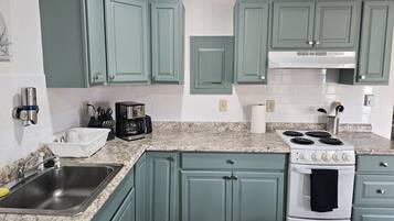 Una cocina con gabinetes verde azulado, una estufa blanca y una encimera de granito.