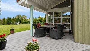 A covered patio with a table and chairs, potted plants, and a view of the backyard.