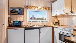 A modern kitchen with wooden cabinetry, a built-in oven, a microwave, and a dishwasher.