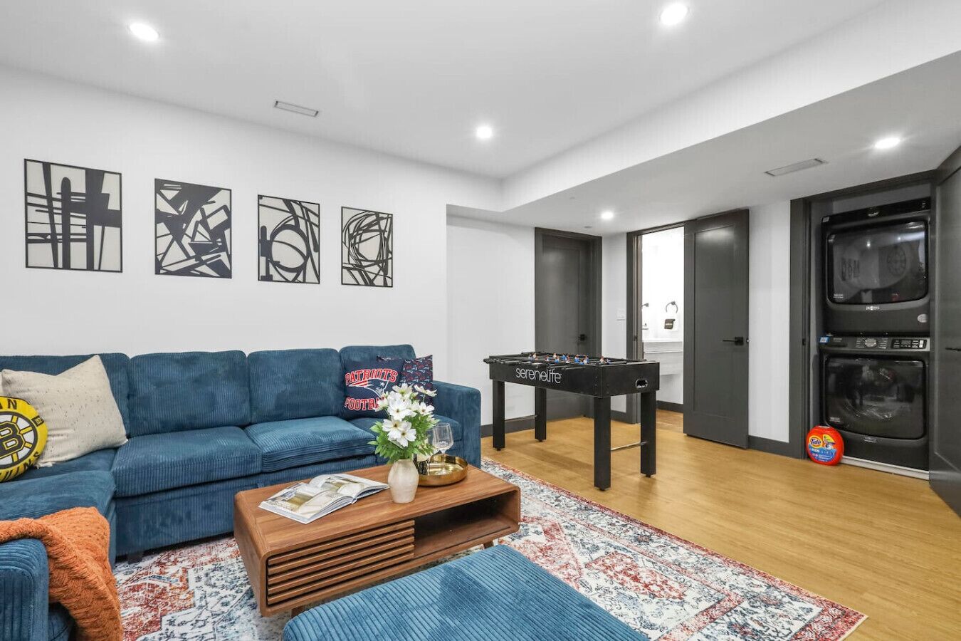 A modern living room with a blue sofa, a foosball table, and abstract wall art.