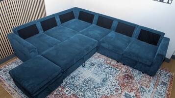 Un sofá modular con un reposapiés a juego, una alfombra estampada y un panel de pared de listones de madera.