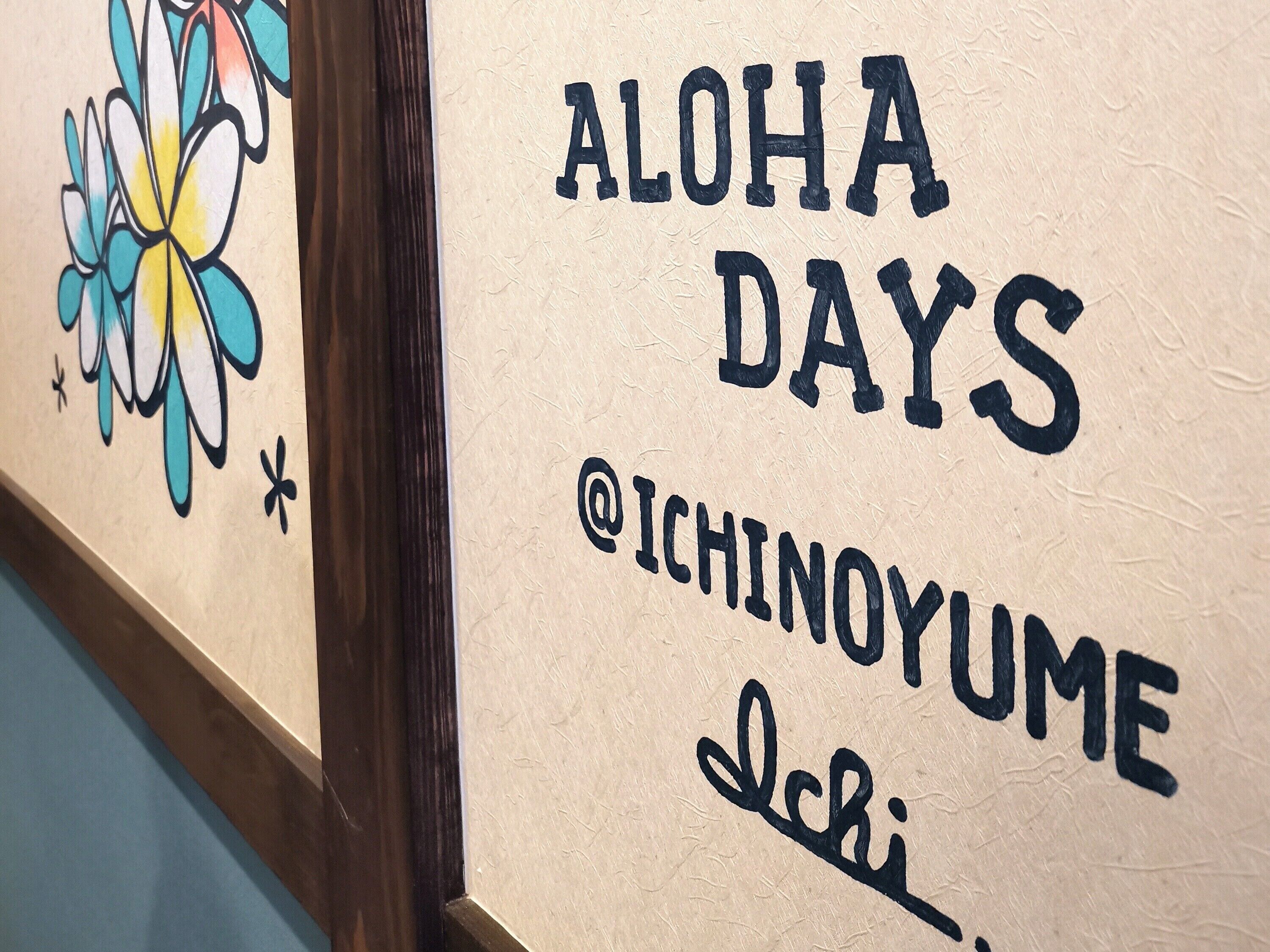 Una pared con el texto 'ALOHA DAYS @ICHINOYUME' y un diseño floral.
