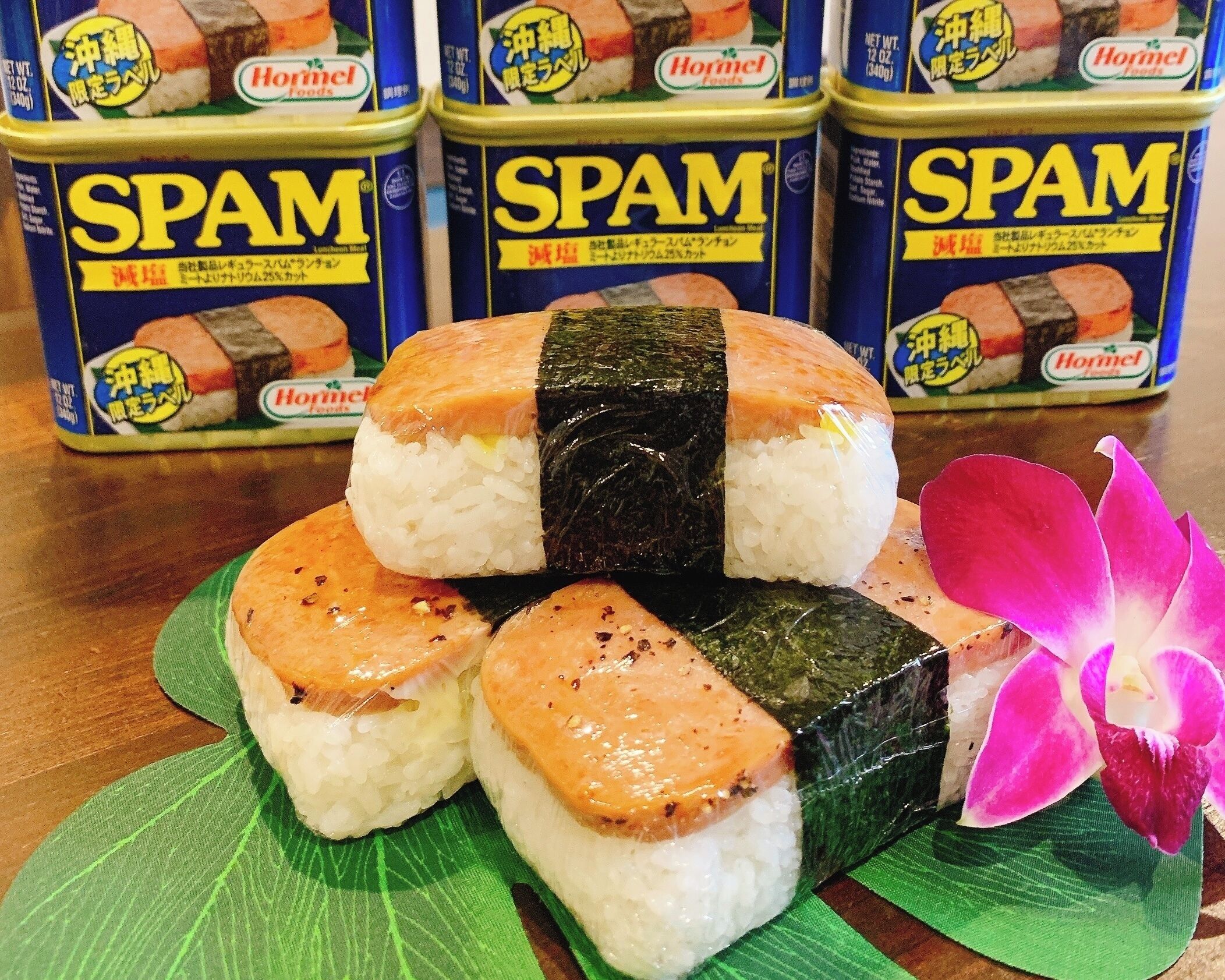 Sushi rolls with seaweed on a green leaf, and cans of Spam in the background.