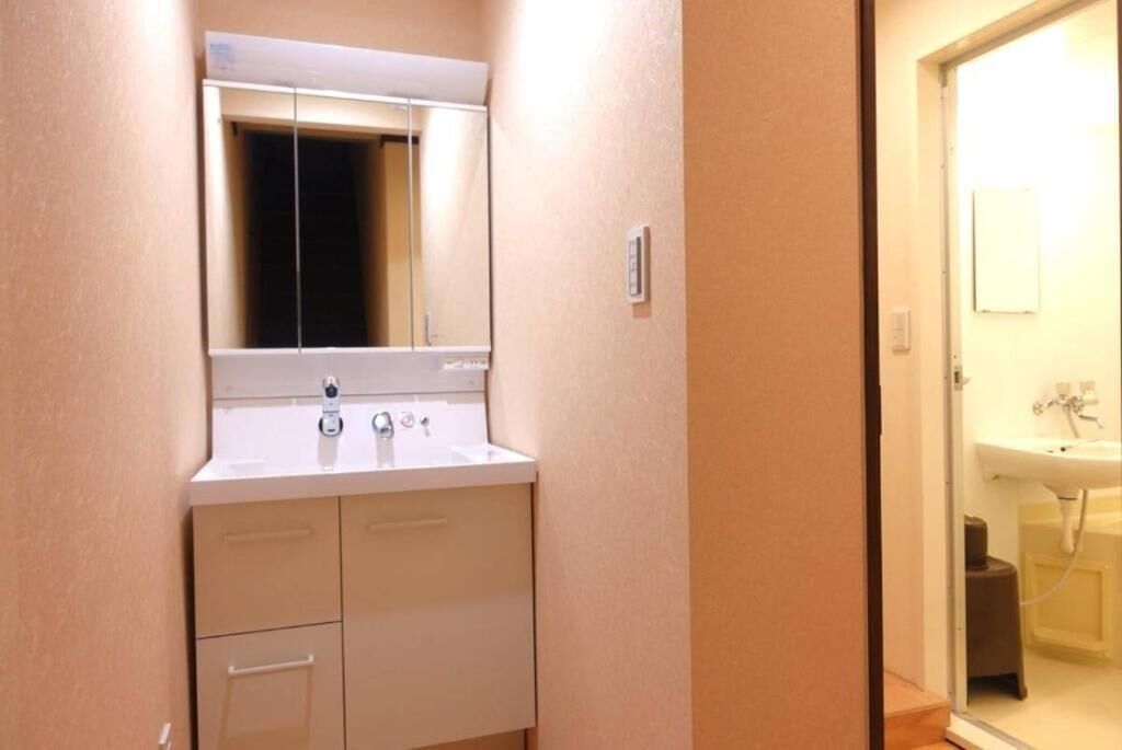 A bathroom with a white sink, mirror, and cabinet.