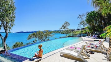 Una piscina al aire libre, sillones reclinables de piscina