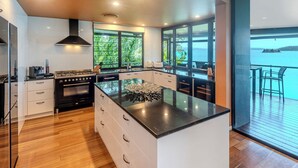 Una cocina moderna con una isla central, ventanas amplias y vista al mar.