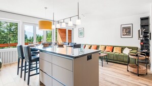 Une cuisine moderne dotée d’un îlot central, de tabourets de bar et de luminaires suspendus.