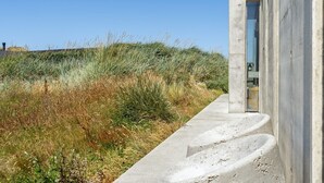 Een betonnen pad dat naar een gebouw leidt, met een groot glazen raam.