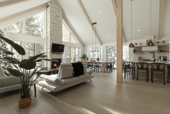 A spacious living area with a fireplace, large windows, and a dining area with bar seating.