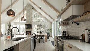 A modern kitchen with a central island, a fireplace, and a dining area. - Spa • Sauna  • Salle de jeux • Terrasse • Foyer (Les Laurentides Regional County Municipality)
