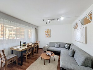 Una sala de estar moderna con un sofá gris, una mesa de comedor de madera y sillas.