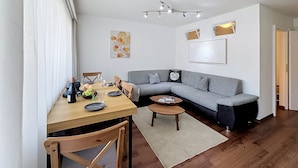 A modern living room with a dining area, a grey sofa, a wooden dining table, and a small coffee table.