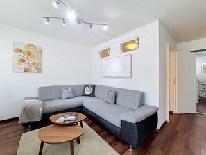 A modern living room with a grey sectional sofa, a round wooden coffee table, and a small rug.