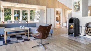 A modern living room with a wooden ceiling, a fireplace, and a dining area with a table and chairs. - "Ephra" - 150m from the sea by Interhome (Bjert)