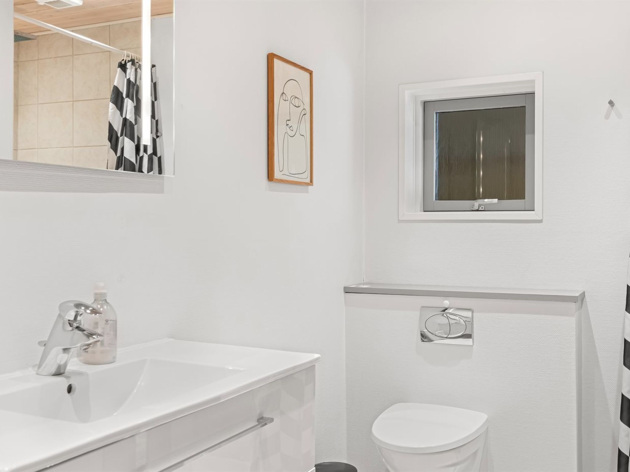 Ein modernes Badezimmer mit einem weißen Waschbecken, einer Toilette und einem Fenster.