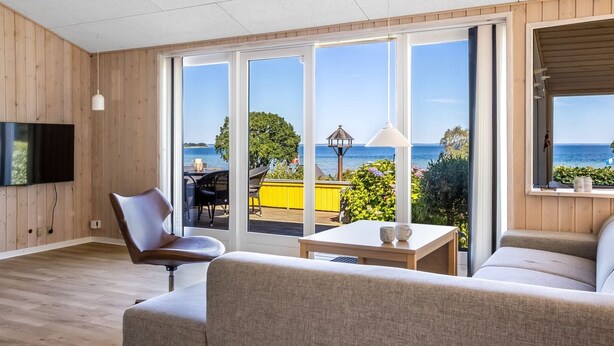 A modern living room with a large sliding glass door leading to an outdoor deck with a view of the sea. - "Ephra" - 150m from the sea by Interhome (Bjert)