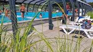 A covered swimming pool area with people swimming and lounging. - 4 Person Holiday Park Home in Malling (Malling)