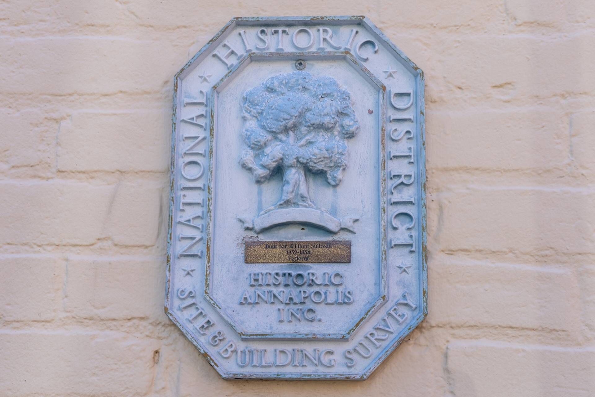 Une plaque représentant un arbre et portant une inscription, fixée à un mur.
