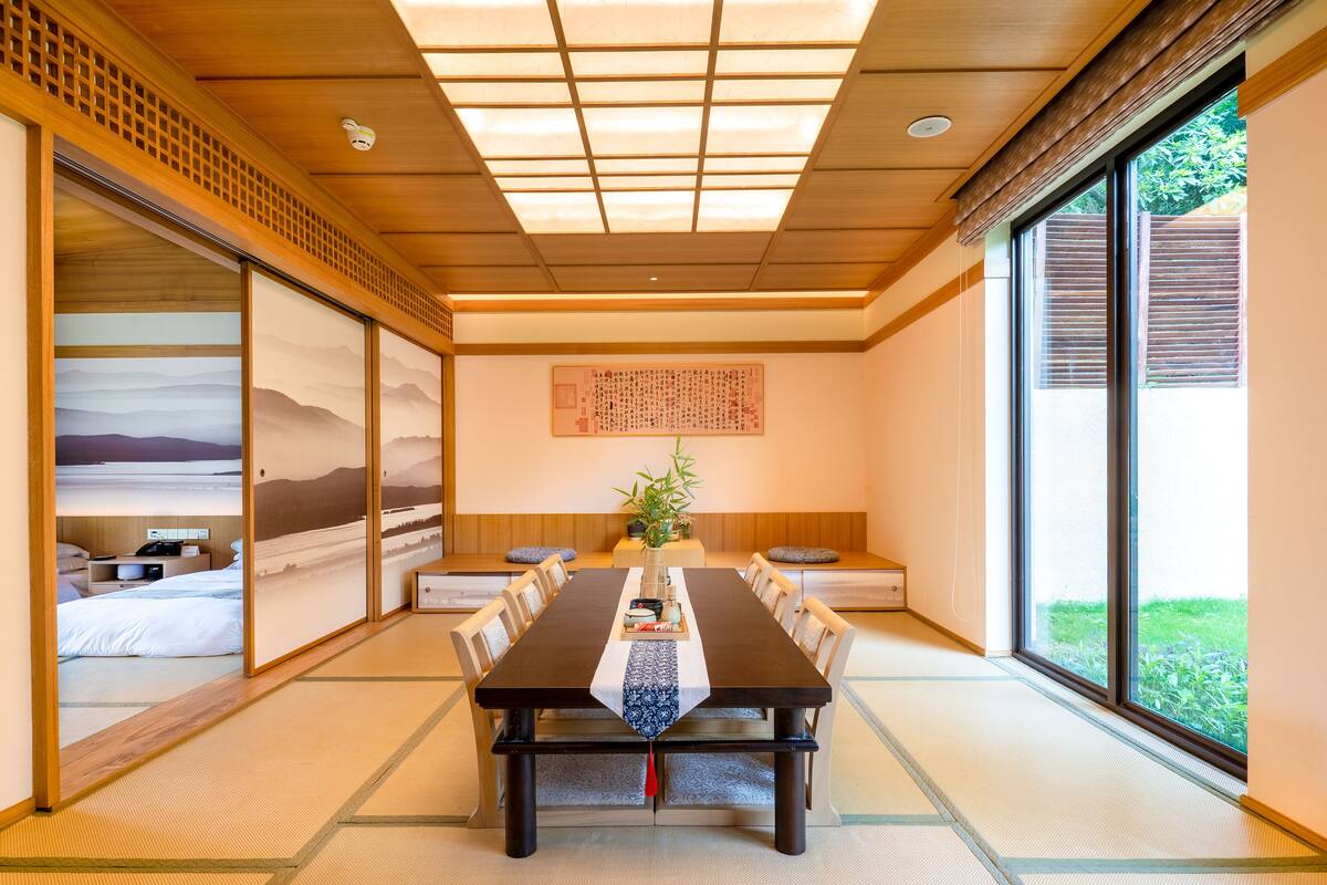 A traditional Japanese-style room with tatami flooring, a low table with a placemat, and sliding doors.