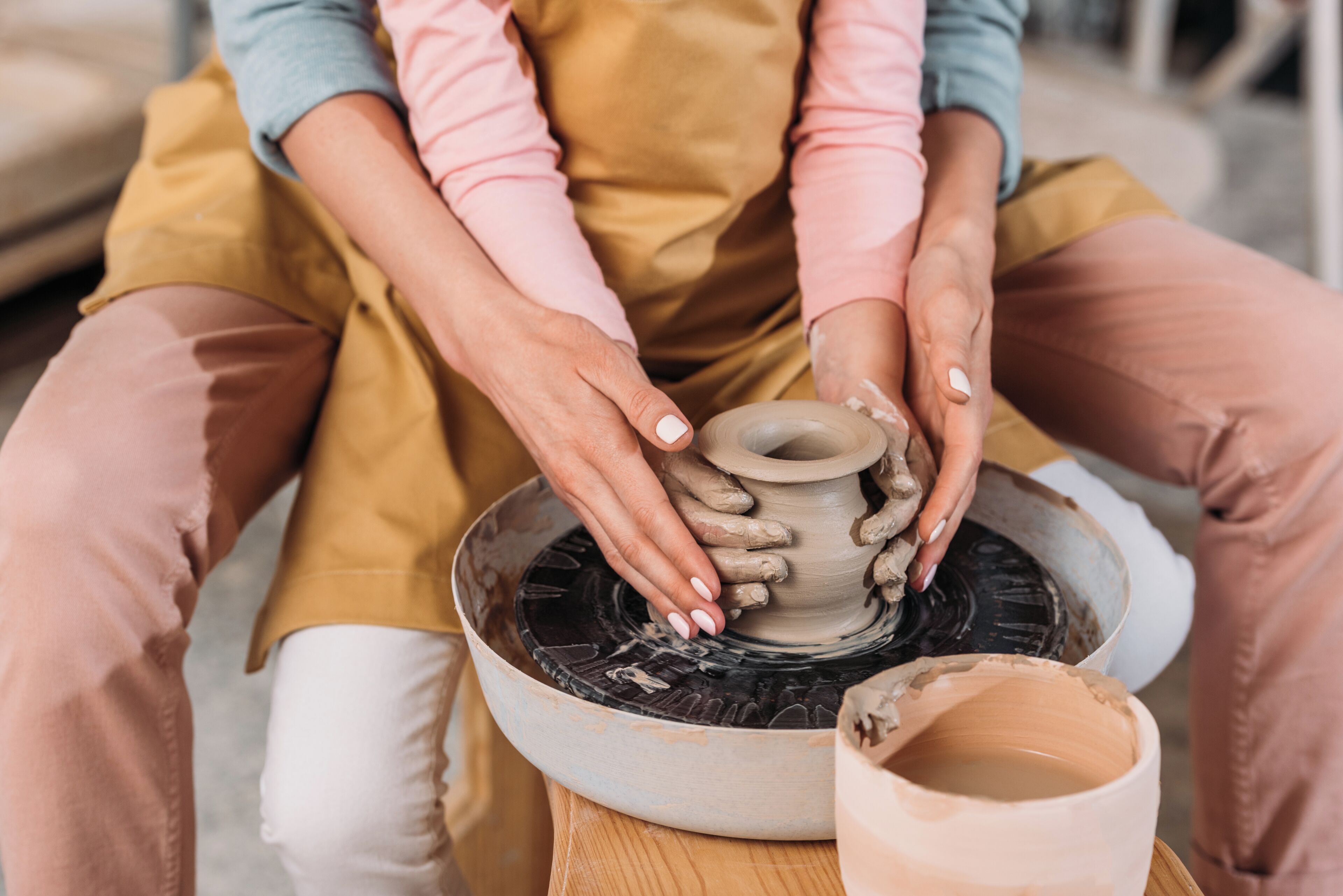 A person shaping clay on a pottery wheel.