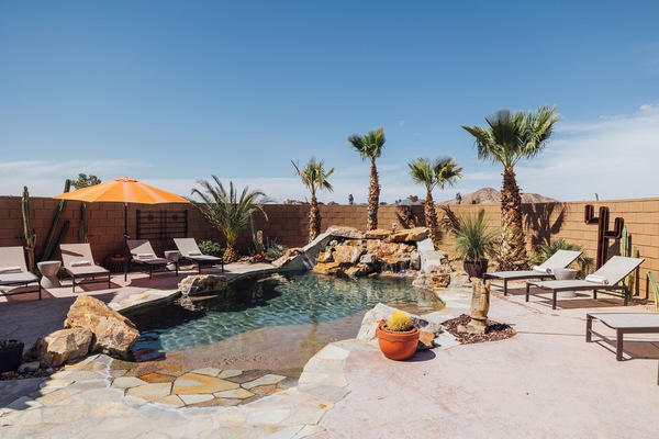 Heated pool with natural rock waterfall and lounge chairs for relaxing.