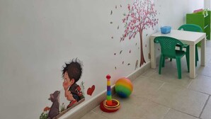 A child's room with a wall mural, a small table, and a green chair.