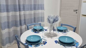 A dining area with a round table set for four, blue chairs, and a white tablecloth.