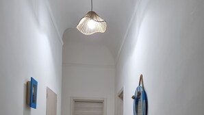 A hallway with a fire extinguisher, a door, and a hanging light fixture.