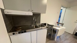 Una cucina compatta con mobili bianchi, un piano cottura in acciaio inossidabile e un lavello a due vasche.