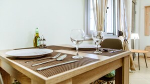 A dining table set with plates, cutlery, and wine glasses, with a bottle of olive oil and a candle on the side. - Lazareta Studio | Nea Chora (Chania)