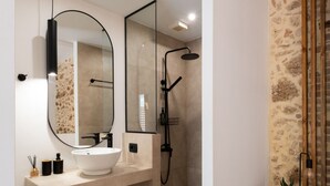 Une salle de bain moderne avec un grand miroir, un lavabo et une douche.