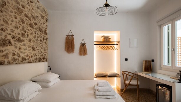Une chambre à coucher avec un lit, un bureau et une chaise. Il y a une fenêtre donnant sur l’extérieur.