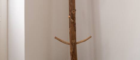 A wooden coat rack in a corner with a granite floor and a white door.