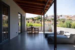 Ein moderner Balkon mit Holzboden, einem Esstisch mit Stühlen, einer Couch und einem Topfpflanzen.