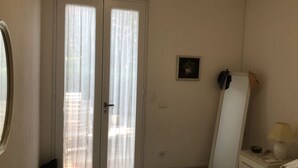 Una habitació amb una porta doble, un quadre petit al mur, un mirall, una làmpada i un armari.