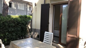 Zona d'estar a l'exterior coberta amb taula i cadires, una porta negra i una porta corredissa de vidre.