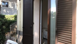 Un edifici residencial amb una porta corredissa de vidre que dona a un balcó amb una cadira blanca.