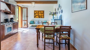 A spacious kitchen with wooden cabinets, a built-in oven, and a dining area with a wooden table and chairs. - Il Castello by Interhome (Montescudaio)