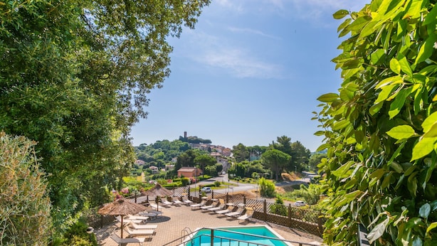 A pool area with lounge chairs and a view of a town in the background. - Il Castello by Interhome (Montescudaio)